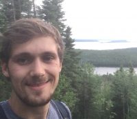 man on a hill with lake in the background