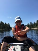woman in a canoe with a dragonfly on her hand