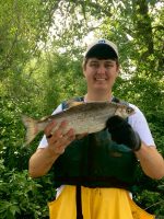 man holding a fish with a forest background